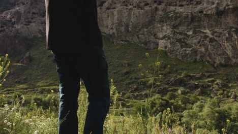 man taking photos of cave monastery in mountain, vardzia, georgia, tilt up