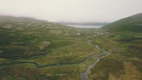 Forward-elevating-drone-shot-over-a-lake-and-a-river-next-to-Nordkapp