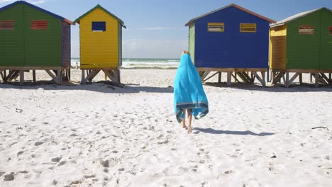 chica con toalla caminando en la playa 4k