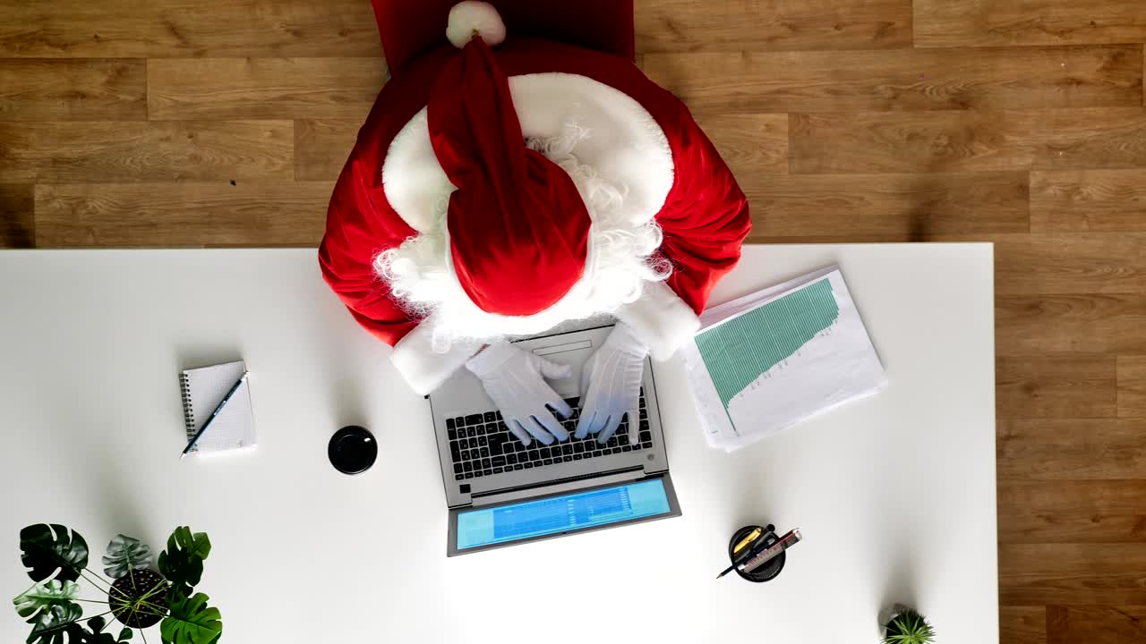 사무실에서 노트북으로 일하는 산타클로스, 타이핑, 공중 전망, 위에서 아래로 찍은 사진, 돌리 찍은 그림