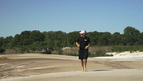 Young-hispanic-male-running-over-sandy-beach-from-a-lake-in-the-Belgian-forest