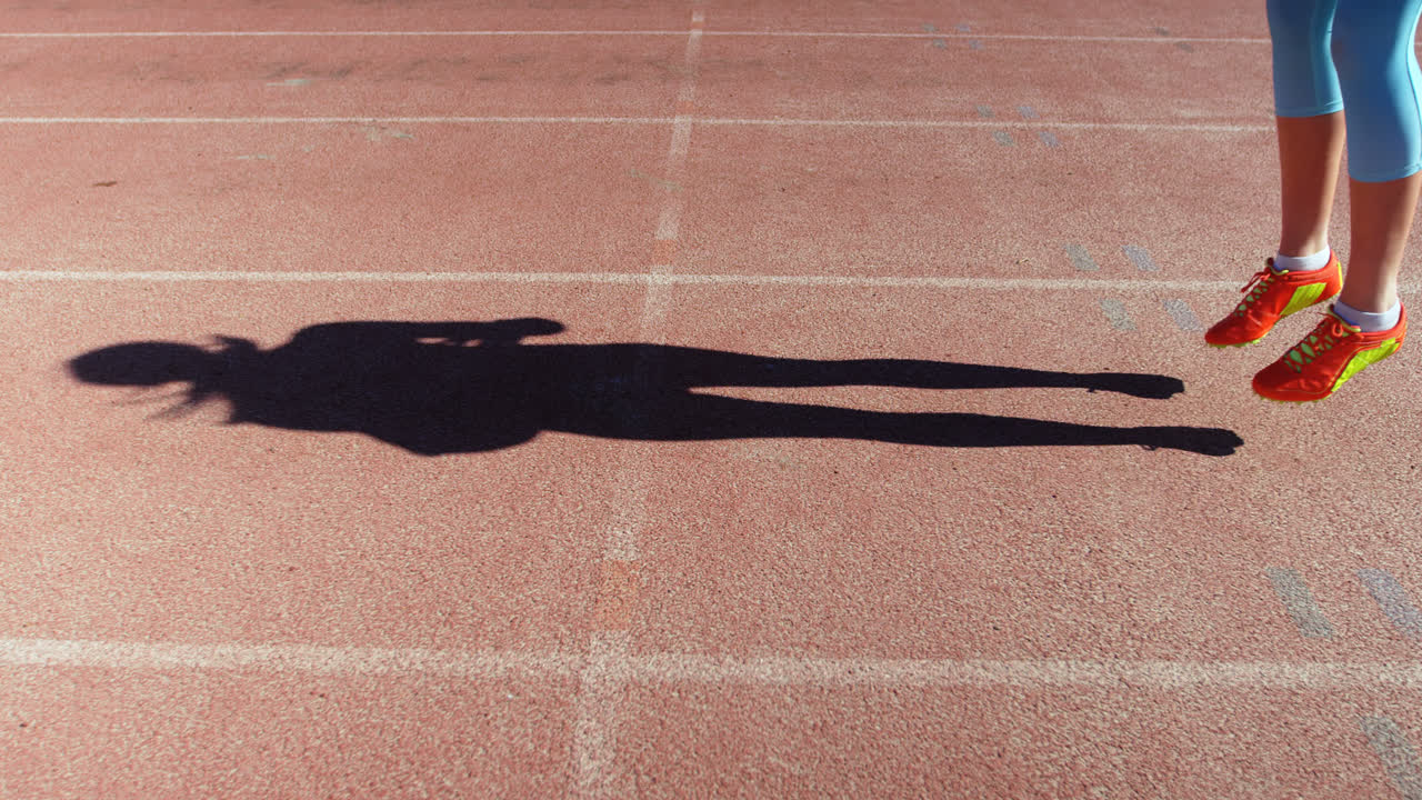 스포츠 장소의 경주 트랙에서 운동하는 여성 선수의 낮은 섹션 4k