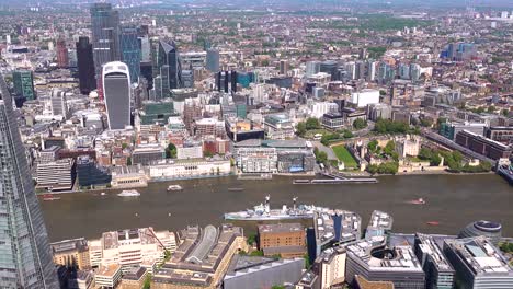 Aerial-view-from-Tower-Bridge,-past-City-Hall-and-HMS-Belfast-to-the-City-of-London,-the-Shard-and-London-Bridge