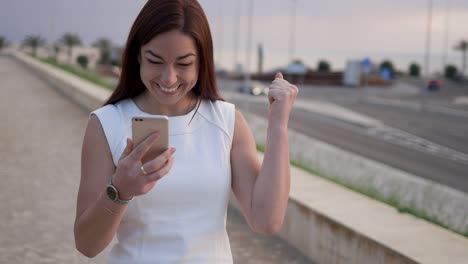 smiling redhead woman reading good news from smartphone.