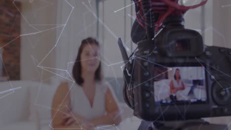 animación de la red de conexiones a través de la pantalla de la cámara con una vlogger femenina grabando vlog en casa