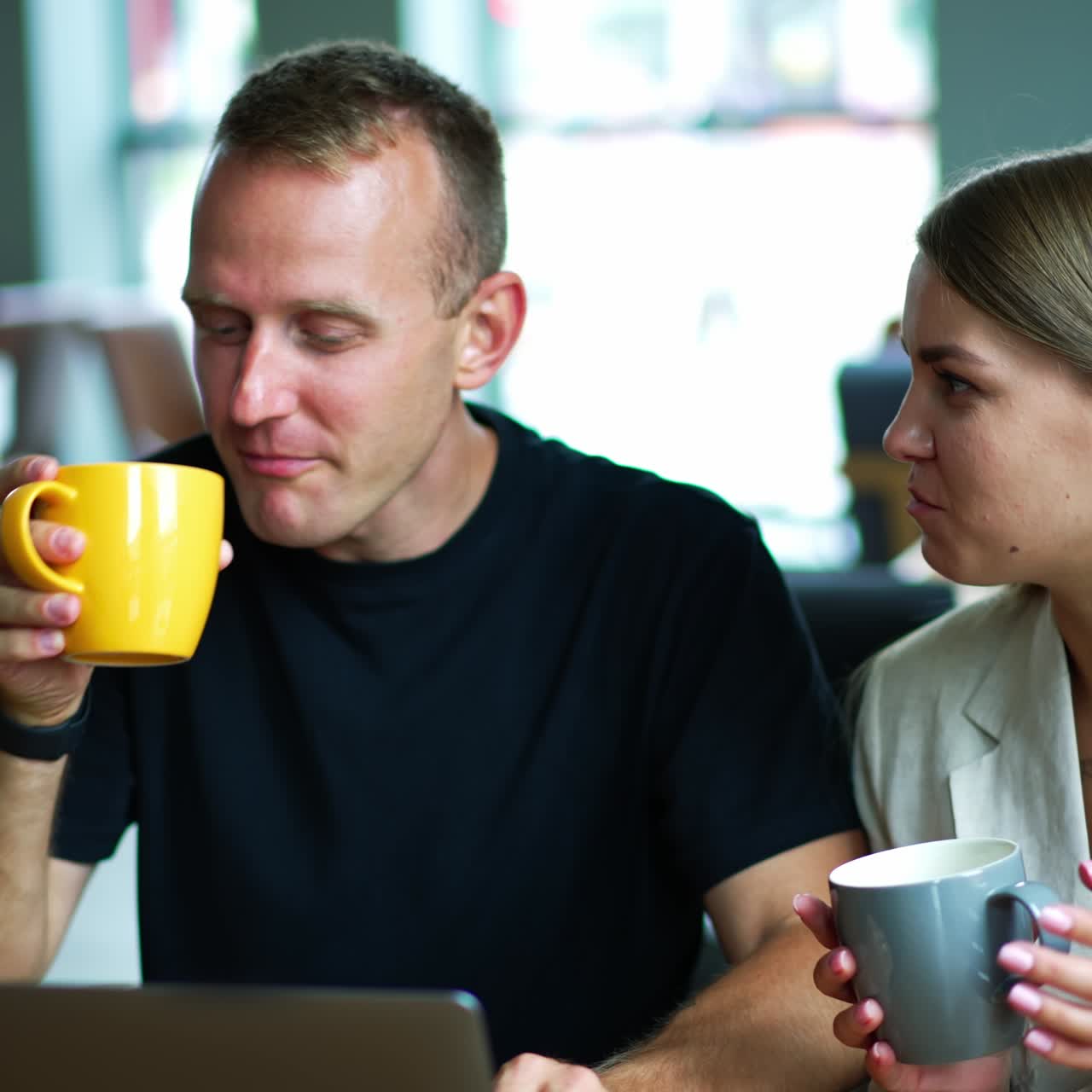 Young married couple enjoying coffee and good talk in a café. Spouses communicating and combining work and rest. Close up