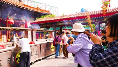 people praying with incense at a temple