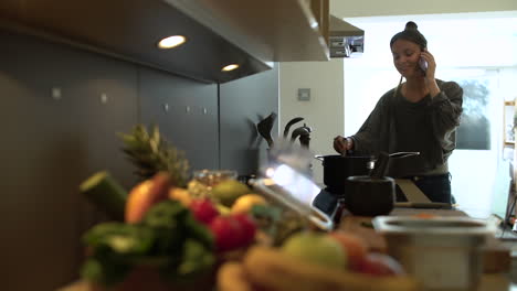 Plano-General-De-Mujer-Joven-Cocinando-Mientras-Habla-Por-Teléfono