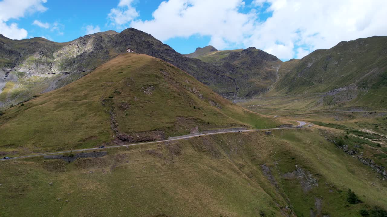 Discesa aerea sotto la Strada Serpentina Transfăgărășan tra montagne lussureggianti e verdi a mezzogiorno.