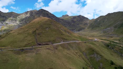 Aerial-descend-below-Transfagarasan-Serpentine-Road-lush-green-mountains-at-midday