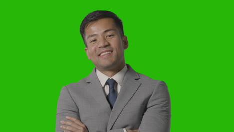 portrait of businessman in suit against green screen smiling at camera 1