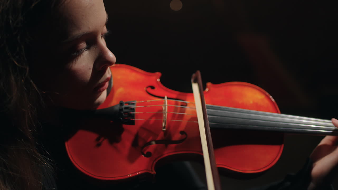 mujer talentosa con violín rojo está tocando en la orquesta sinfónica en la escena de la sala de música retrato