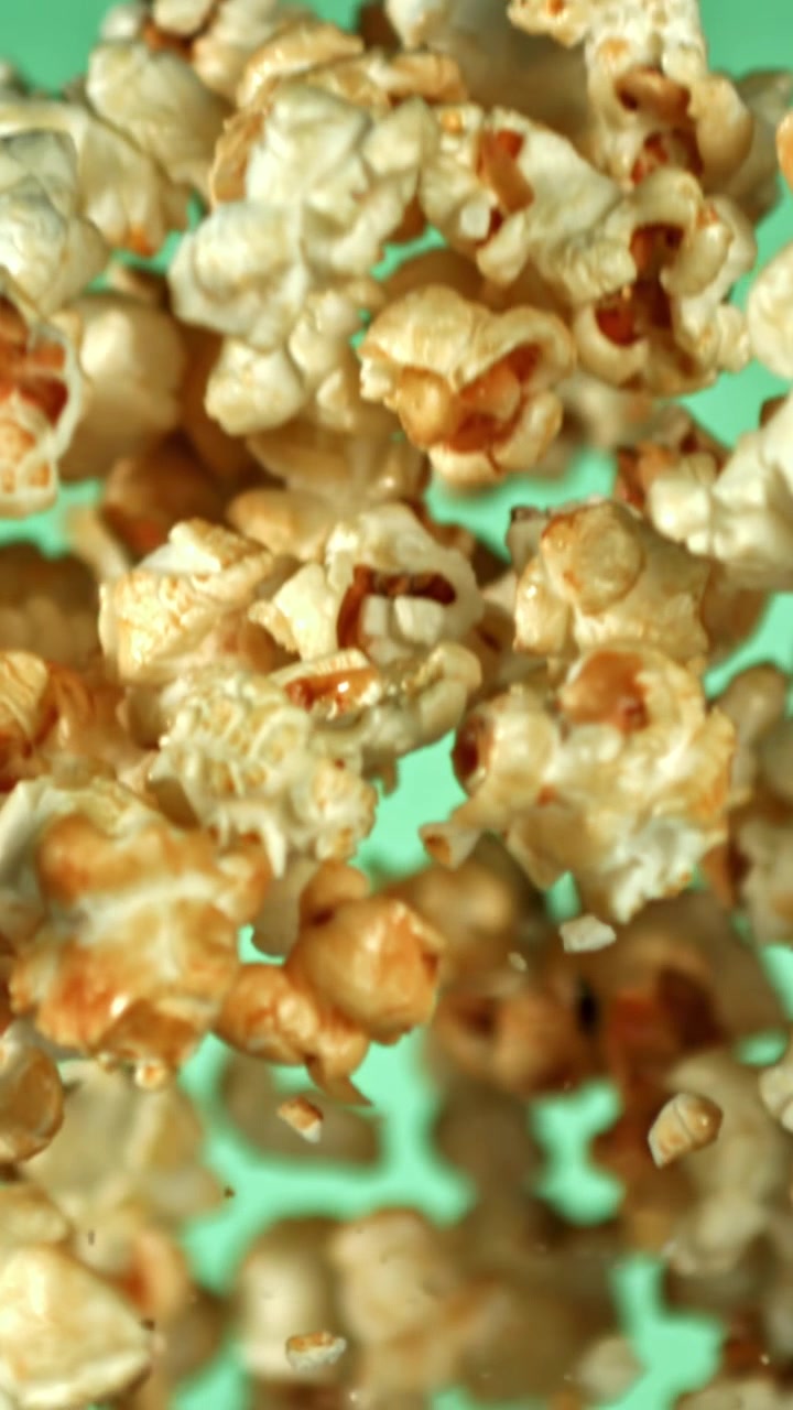Sweet Caramel Popcorn Falling in Slow Motion on Green Background