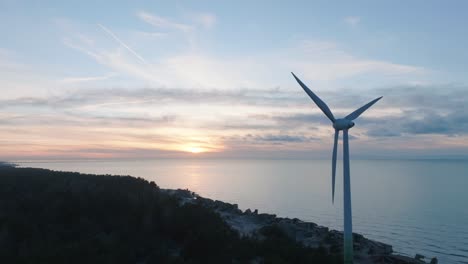 aerial establishing view of abandoned seaside fortification buildings at karosta northern forts on the beach of baltic sea in liepaja, sunset, golden hour, wind turbine, wide drone shot moving forward