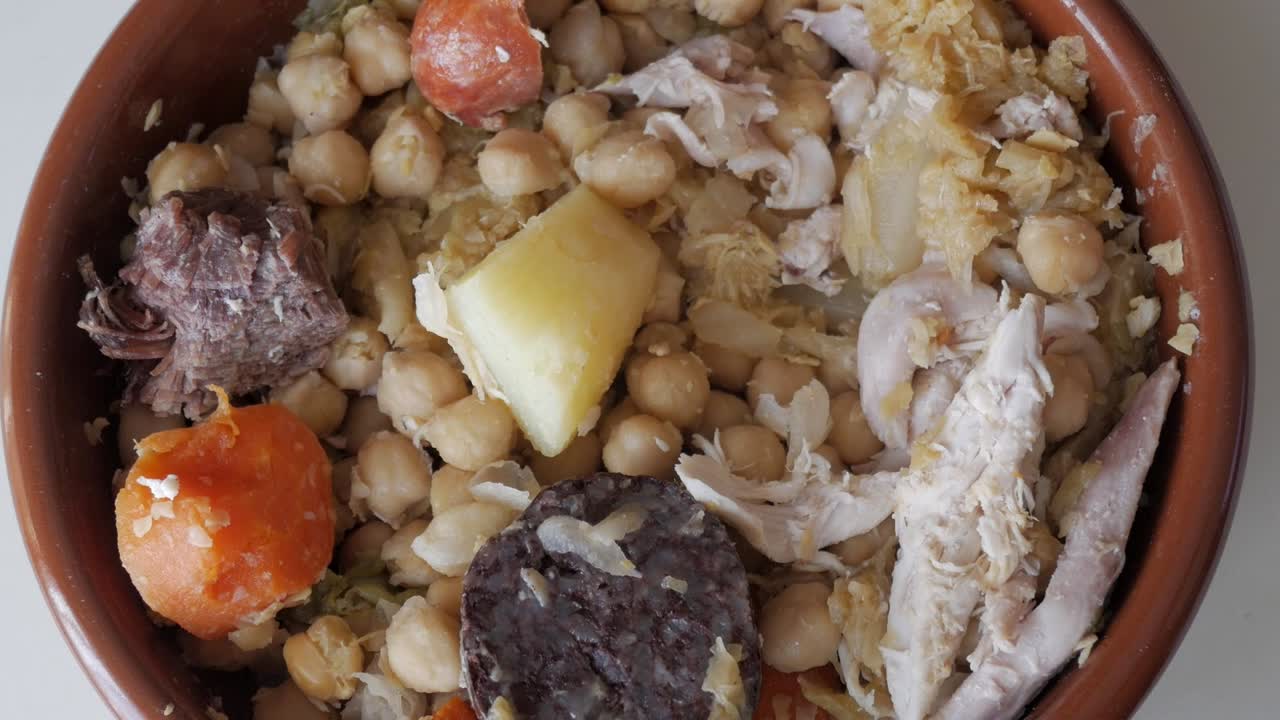 Traditional Spanish cocido with vibrant ingredients in a clay bowl