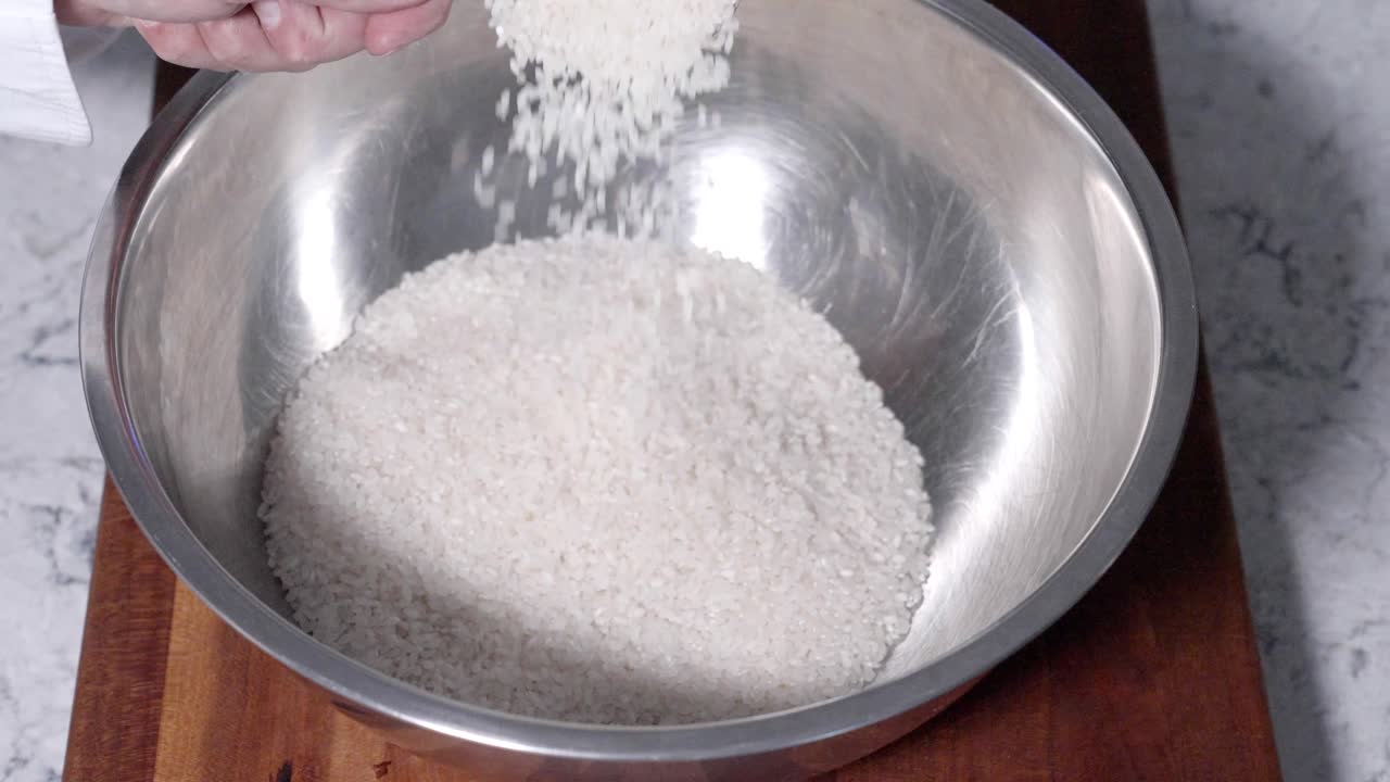 “Static downward shot of rice pouring into a bowl, showcasing the texture and flow of the grains. Ideal for cooking tutorials, food preparation, and culinary content.”