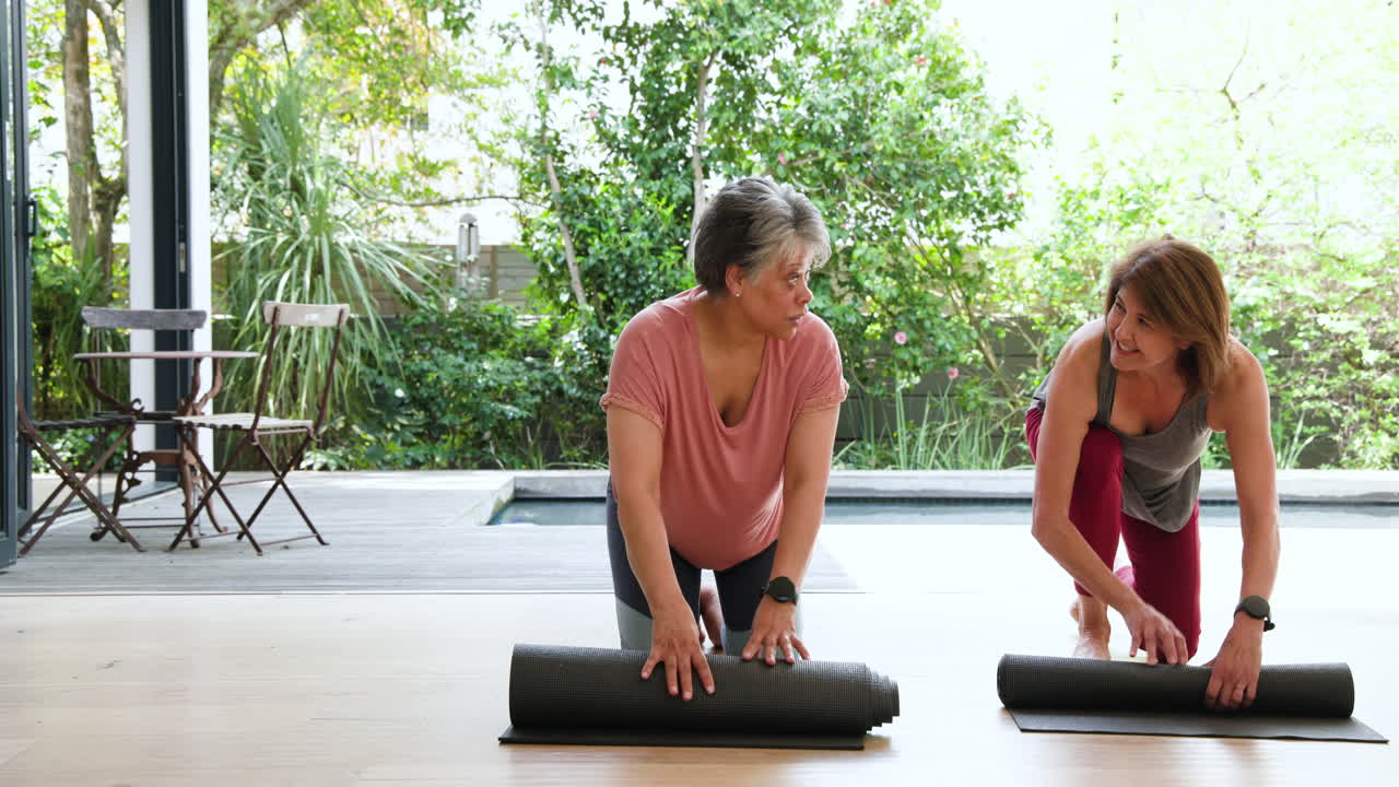 Senior women enjoying yoga together outdoors, smiling and holding mats