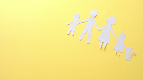 Close-up-of-family-with-cat-made-of-white-paper-on-yellow-background-with-copy-space