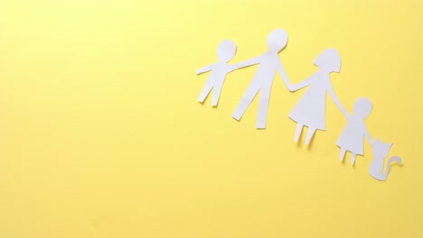 close up of family with cat made of white paper on yellow background with copy space