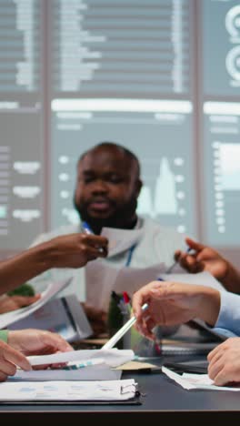 vertical video close up of diverse specialists evaluating data numbers on archived files