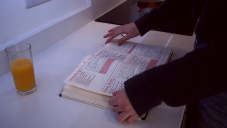 female model looking through a cookbook on a kitchen worktop then closing the book up and walking off