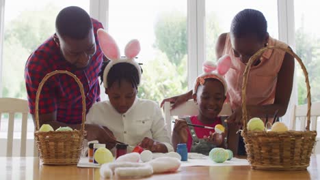 african american family painting easter eggs together at home