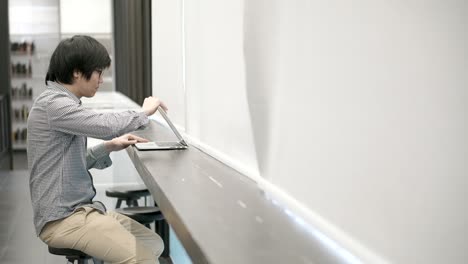 joven hombre de negocios asiático usando una computadora portátil en el espacio de trabajo. mano masculina escribiendo contraseña en el teclado de la computadora portatil para iniciar sesión. estilo de vida independiente en el concepto de la era digital.