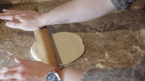 Rolling-out-pizza-dough-on-a-kitchen-surface