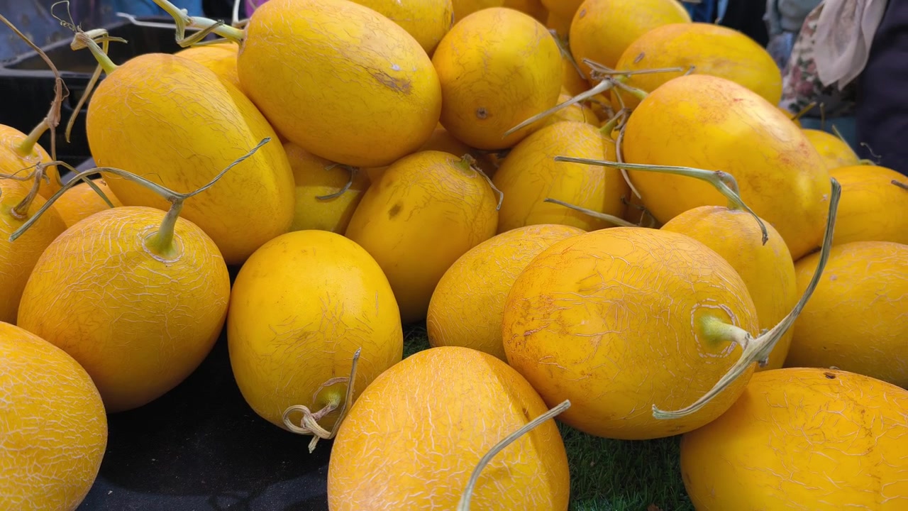 Meloni canarini freschi sono impilati ordinatamente su un tavolo per l'esposizione. Questi frutti giallo brillante sono pronti per la vendita in un mercato locale.