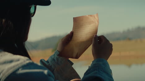 woman reading a vintage letter by a lake