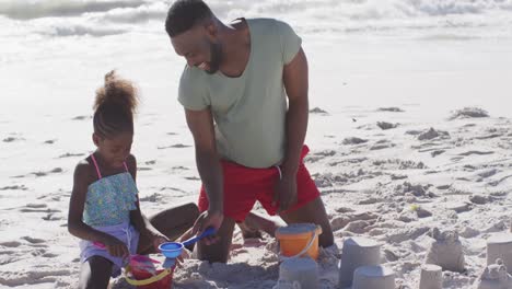 Video-Eines-Glücklichen-Afroamerikanischen-Vaters-Und-Seiner-Tochter,-Die-Am-Strand-Mit-Spielzeug-Spielen