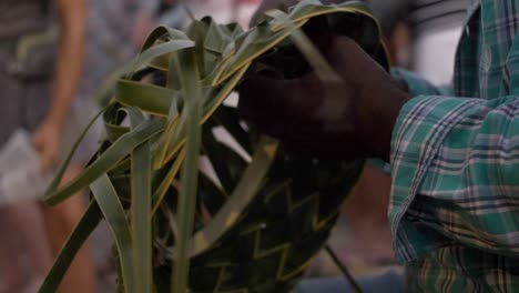 el hombre crea un sombrero con sus manos a partir de una hoja de palma