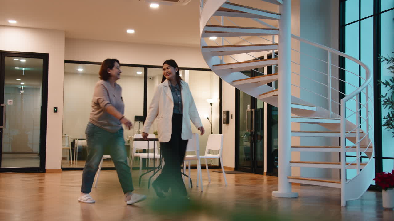 Due donne che camminano in un ufficio moderno con una scala a chiocciola