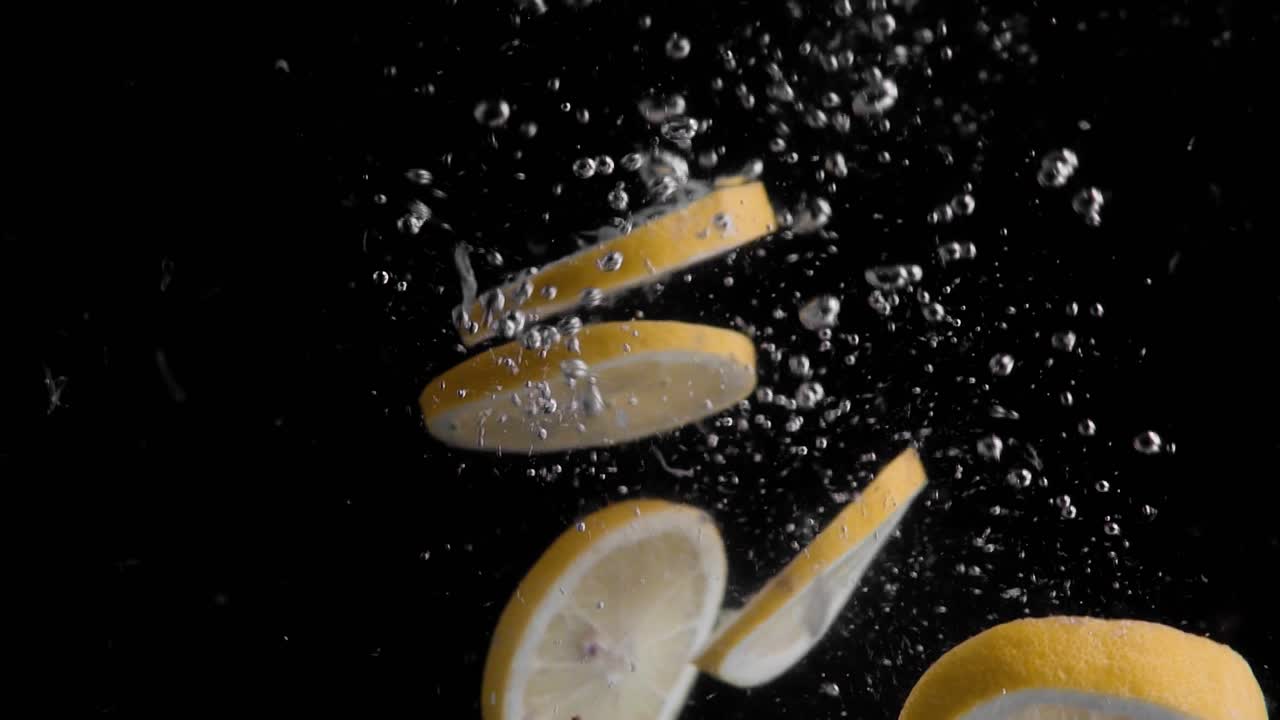 rodajas de limón cayendo al agua en cámara superlenta, fondo negro, muchas burbujas de aire, 4k240fps