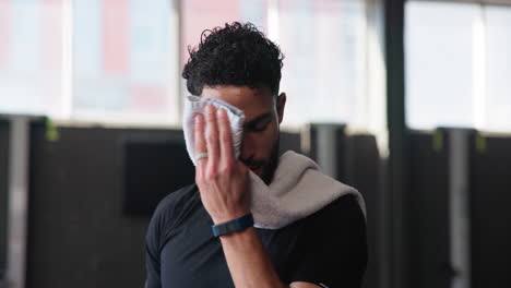 man wiping sweat off his forehead after a workout in the gym