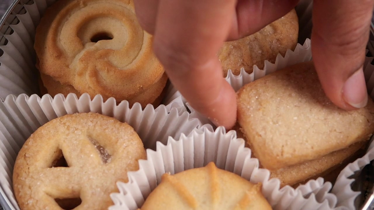 Hand Picking a Butter Cookie from a Tin Box
