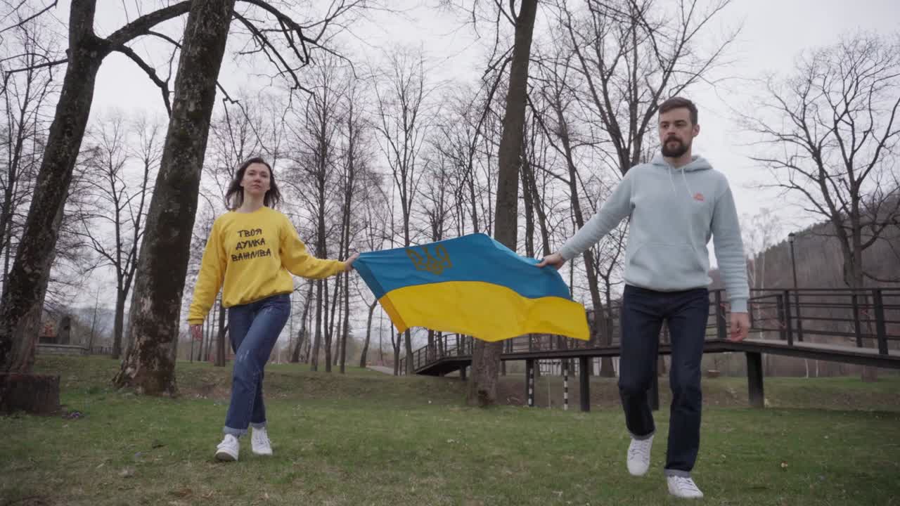 девочка и мальчик держат и ходят с украинским флагом. символ сочувствия. надпись на свитере девушки: "твоё мнение важно"