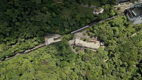 Aerial-following-the-Peak-Tram-as-it-makes-its-down-from-Victoria-Peak,-Hong-Kong