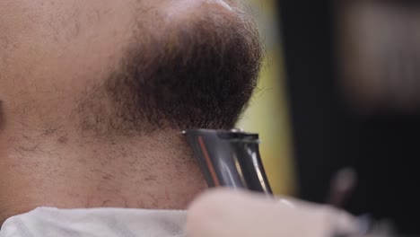 un hombre se corta la barba con una navaja eléctrica