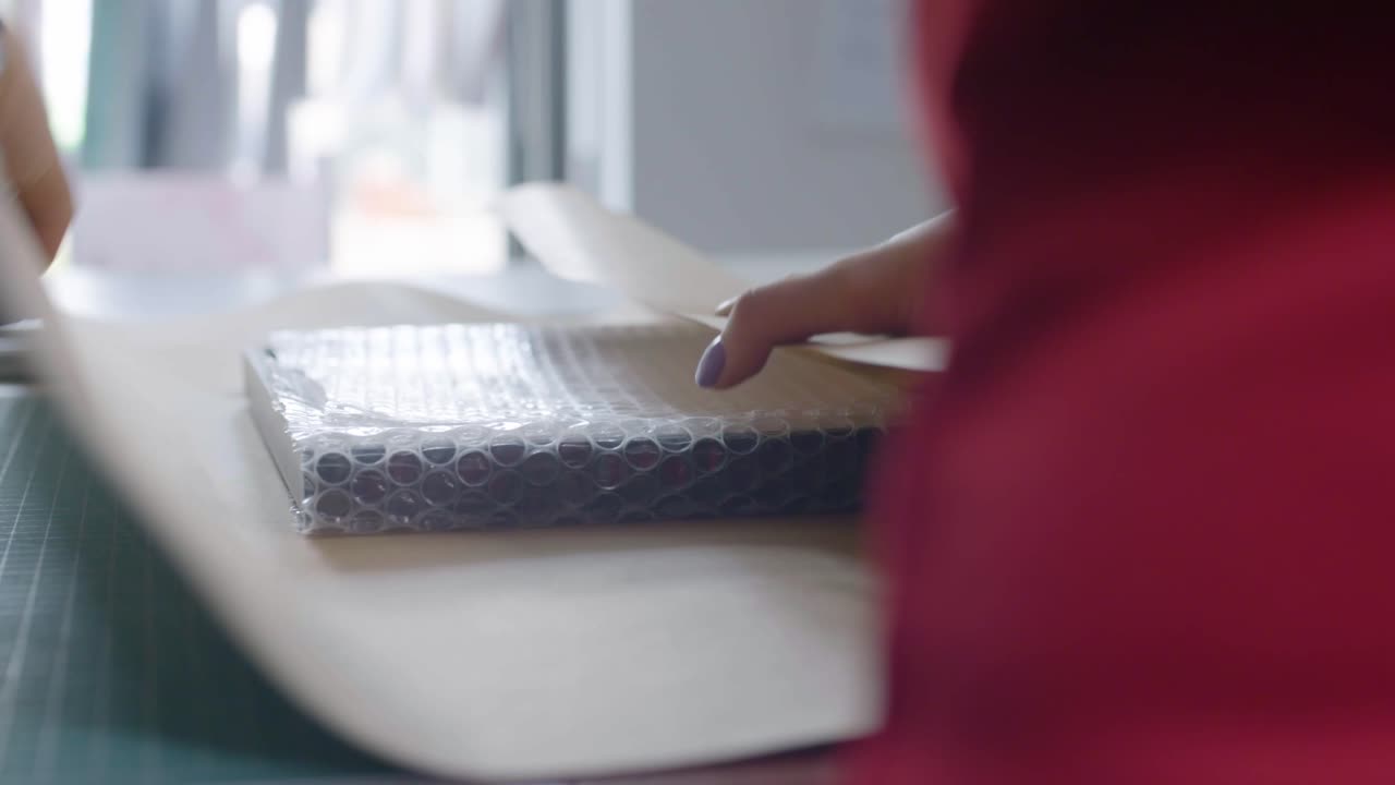 Female wrapping bubbled foil present into gray wrapping paper at the table