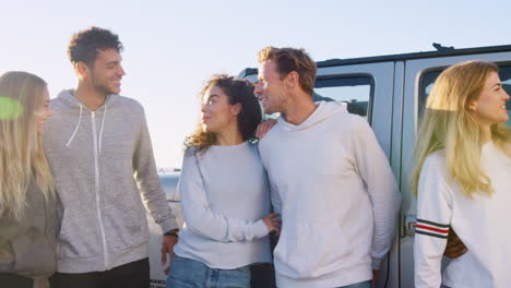 amigos adultos jóvenes en un viaje por carretera de pie junto al coche hablando