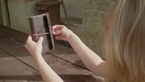 young woman diarist secures personal thoughts in leather book binder