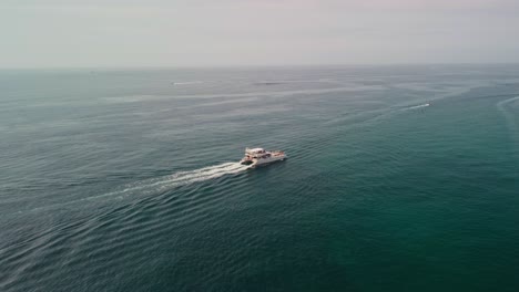 Solitary-boat-cruising-the-calm-waters-near-Puerto-Banus,-Marbella-under-a-clear-sky,-aerial-view