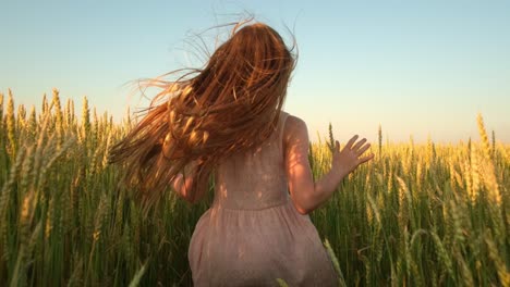 girl running through a wheat field at sunset