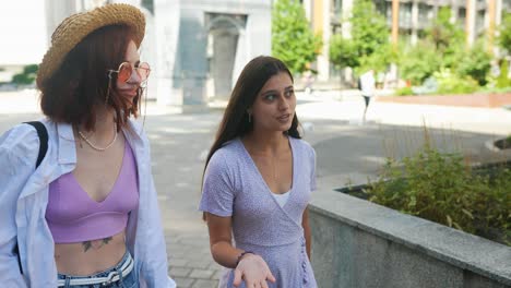 two young women walking and talking in the city