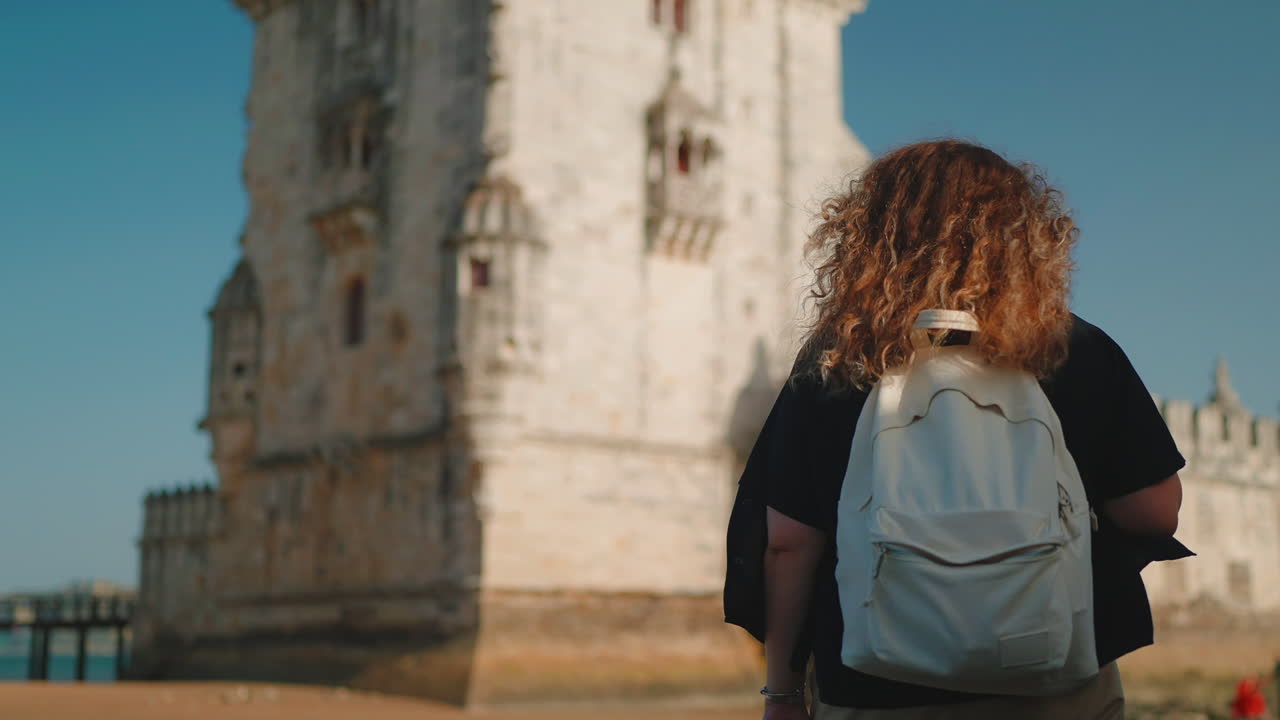 mujer con mochila en la torre de belem, lisboa, portugal