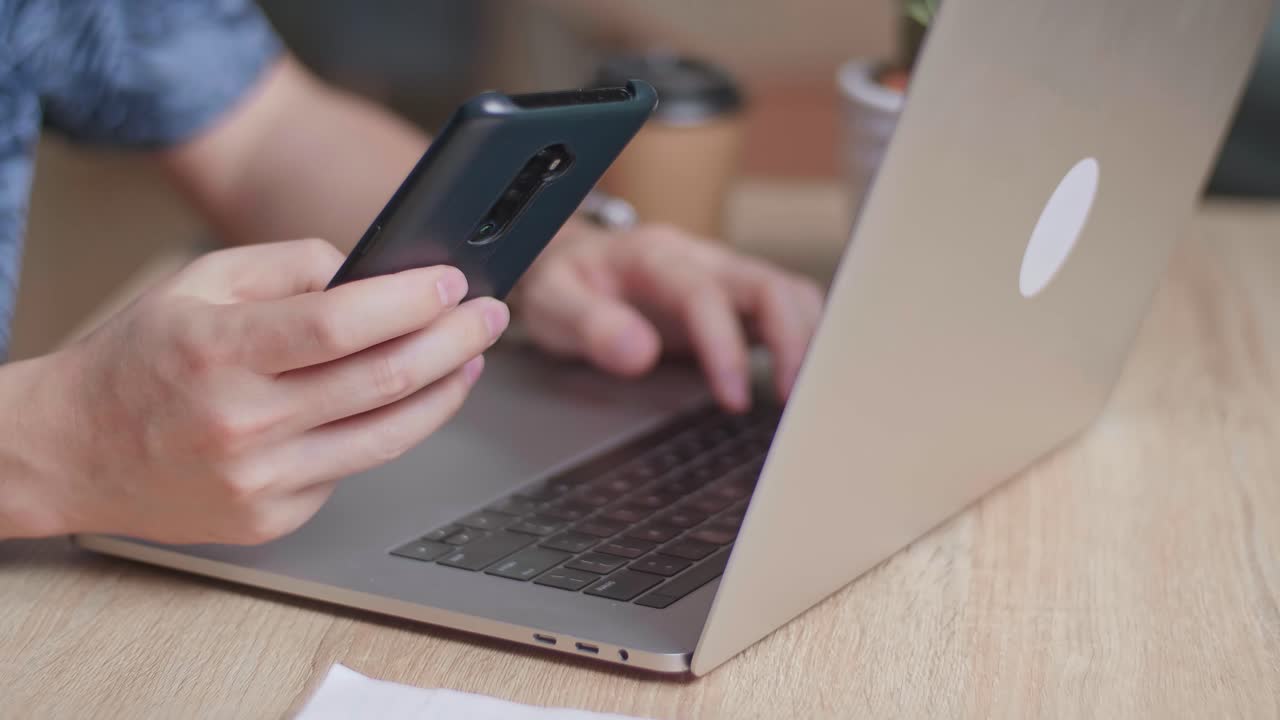 Hands Man Using Mobile Phone During Work On Laptop Computer, Video In 4K