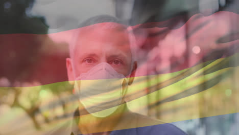 animation of waving germany flag over portrait of caucasian man wearing face mask on the street