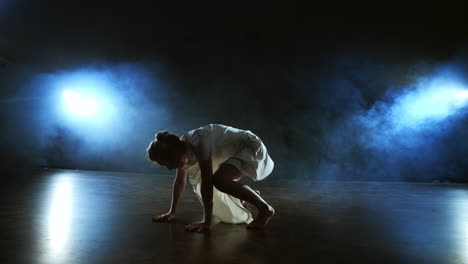 movimiento lento: bailarina de ballet moderno mujer descalza tendida en el suelo haciendo giros y piruetas y saltos.