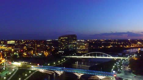 aerial view of a city at night with a bridge and river